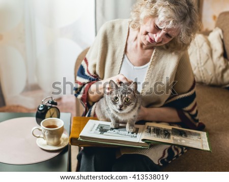 an elderly woman watching photo album with a cat on his lap
