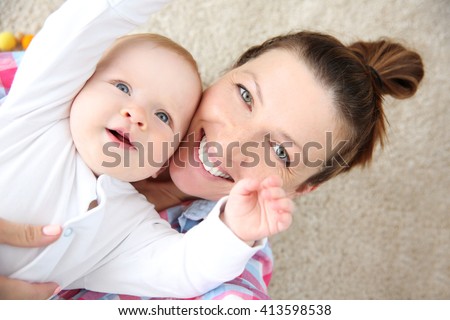 Young mother taking a selfie with her baby on the floor, close up