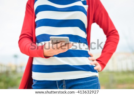 Female holding smart phone in hand on outdoors background. Blank screen with copyspace picture