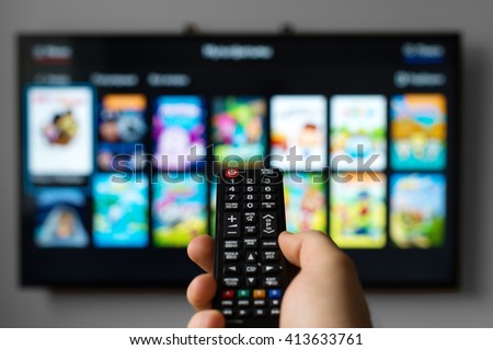 Male hand holding TV remote control. Royalty-Free Stock Photo #413633761