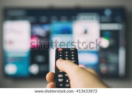 Male hand holding TV remote control. Royalty-Free Stock Photo #413633872