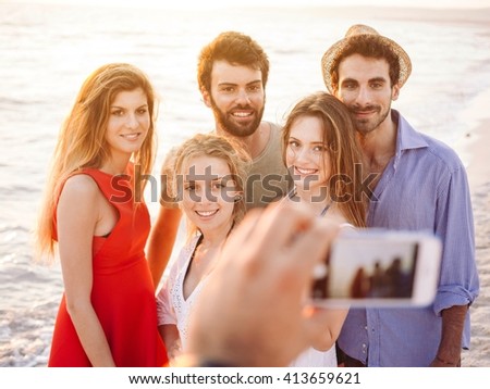 Group of happy friends taking a picture at the beach