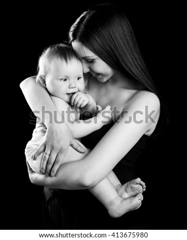 black and white portrait of a happy mother holding her baby, isolated against black studio background