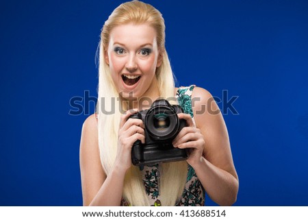 Portrait of a young girl with a camera in his hands on a blue background