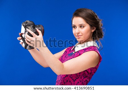 smiling young brunette girl in the hands of the camera in a black shirt on a blue background