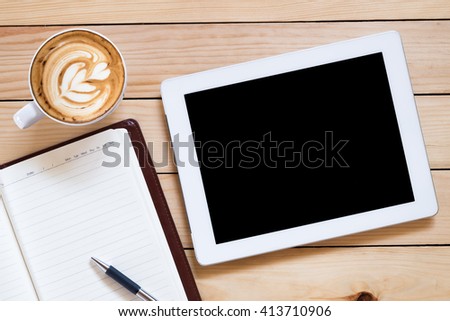 Office workplace with blank screen tablet, notebook, pen and coffee cup on rustic wood table.Top view.Office supplies and gadgets on workplace.Working desk table concept.Flat lay image.
