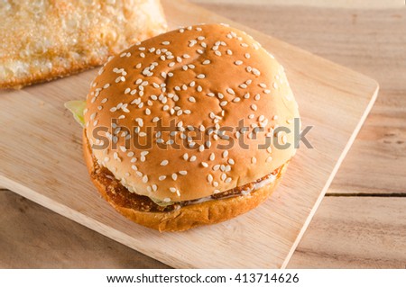 fish burger on wooden pad top with white sesame