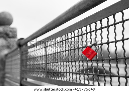 Red love lock padlock with heart on bridge symbol of true eternal love and commitment. Black and white stock photo with selective color effect.
