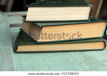 Simple composition with stack of old books with green cover on aged green table. Vintage design