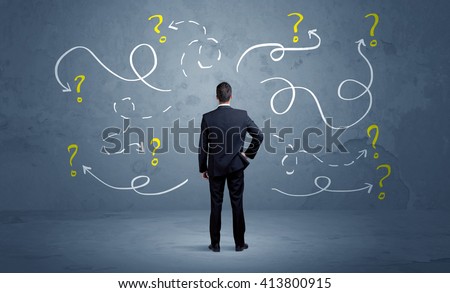 A salesman in doubt can not find the solution to the problem concept with curvy lined arrows and question marks drawn on urban wall Royalty-Free Stock Photo #413800915