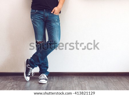 Young fashion man's legs in jeans and sneakers on wooden floor Royalty-Free Stock Photo #413821129