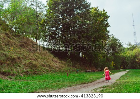 Happy little girl runs in the park