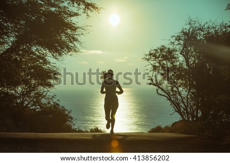 Young woman running outdoors early morning.  Royalty-Free Stock Photo #413856202