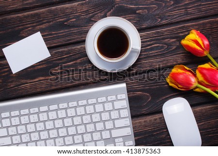Keyboard with tulips on the table. The first spring flowers on the boards