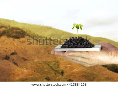 seed growing over a smartphone in male hand. on the mountain Thailand, most of which fall into the drought because of deforestation.