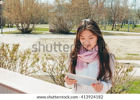 Asian woman using digital tablet in park