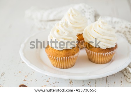Vanilla cupcakes on white wood background, copy space