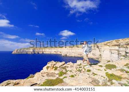 Men taking picture of a coast line near Azure Window on Gozo Island, Malta