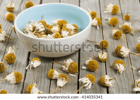 dried chamomile flower heads on old wood table 