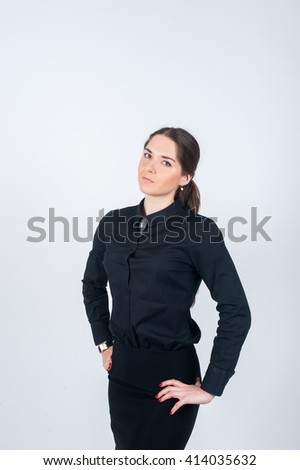 Business woman stands in strict black shirt, resting his hands on her hips. Vertical photo on white background