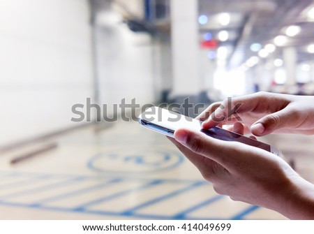 Girl use mobile phone, blur image of disabled parking as background.