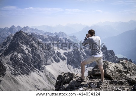 Hiker photographing on the summit of the Allgau Alps