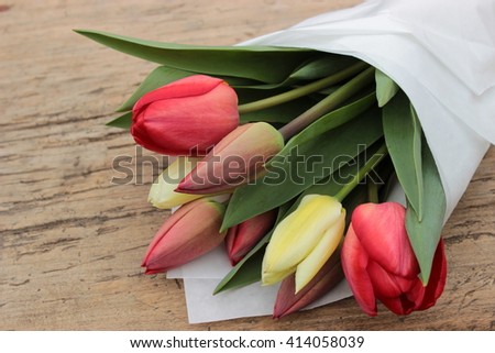 Simple composition with great bouquet of red and white tulips on old rustic wooden background. Vintage design