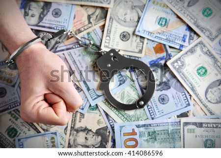 Man in handcuffs clenching fist on dollar banknotes background