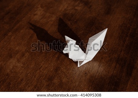 A squirrel origami made of white paper isolated on wooden background.