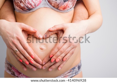 Pregnant woman and her husband holding baby bump