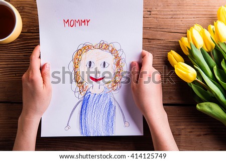 Woman holding drawing of her from her daugter. Tulips.