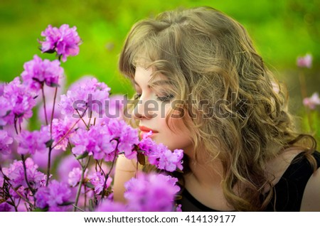Young girl in long black dress smelling chinese cherry in blossom