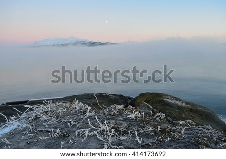 heavy sea ice fog over fjord landscape with dense ice fog and vibrant colorful dawn sky