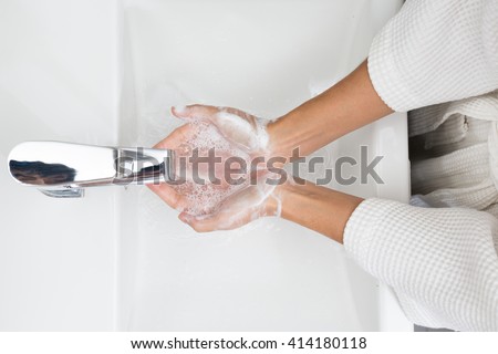 Woman in a bathrobe is washing hands. Royalty-Free Stock Photo #414180118