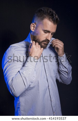 A businessman is putting on his shirt.