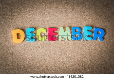 Colorful wooden word DECEMBER on cork board with selective focus