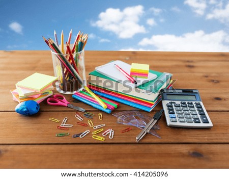 education, school supplies, art, creativity and object concept - close up of stationery on wooden table over blue sky and clouds background