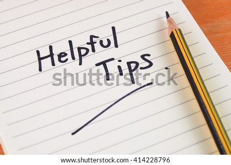 handwriting word helpful tips on note paper with pen wooden desk background