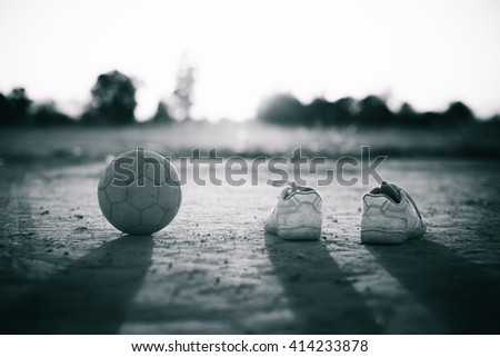 an old ball with the shoes for street soccer football under the sunset ray light. Black and white picture style.