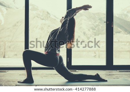 Young beautiful woman practicing yoga with mountain view in the background. Freedom concept. Calmness and relax, woman happiness. Toned picture