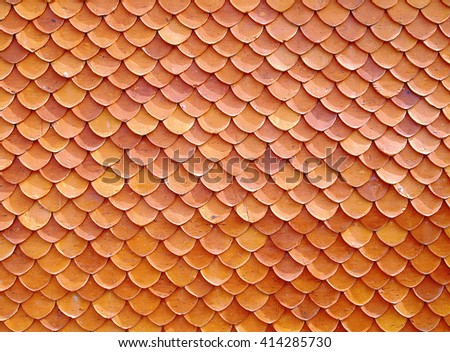 repetitive wave pattern or fish scale striped of orange roof clay tile of temple or thai antique house, terracotta roofing, asian traditional exterior architecture detail, abstract texture background