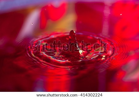 Macro photo of water drops falling into a pool of water, causing a splash and ripples