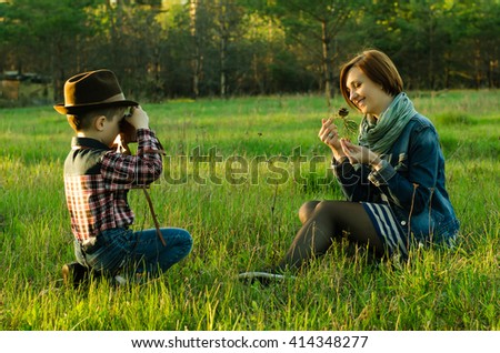 Happy boy with vintage film camera photographing model withs nature