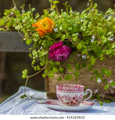 Cup of coffee on the table in the garden with background of flowers.