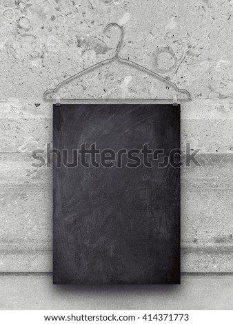 Close-up of one blank blackboard frame hanged by clothes hanger against grey marble stone wall background