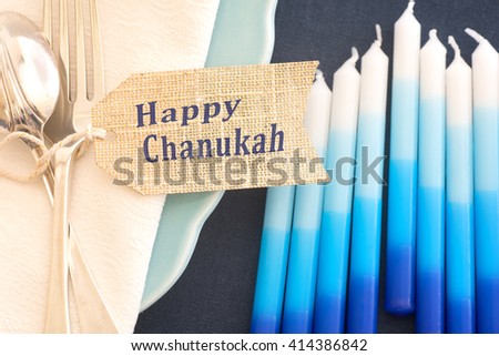 Above View Closeup of Chanukah Table Place Setting with Candles, Plates, Silverware, Napkin, and Name Tag with Room or Space for your words, text, or copy over blurred candles.  Horizontal warm tone