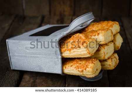 Bread sticks with cheese in iron box on wooden background. Selective focus. Toned image