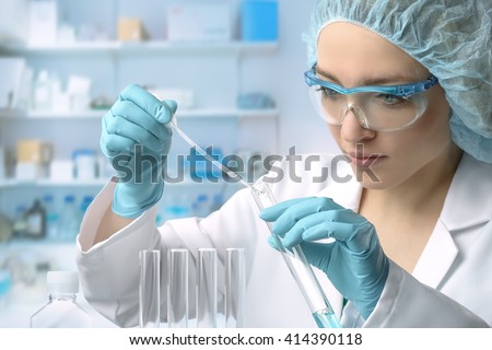 Young female tech or scientist loads liquid sample into test tube with plastic pipette. Shallow DOF, focus on the hand with the tube. Royalty-Free Stock Photo #414390118