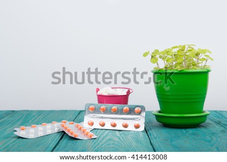 Many different pills in a pink bucket and flower on blue wood desk and white background