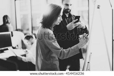 Creative managers meeting.Art director working with colleague designer startup project.Woman drawing new idea,analyze marketing plans.Blurred background,light effects,film effect.Wide,black and white